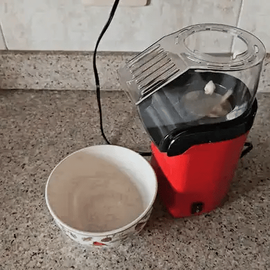 La máquina de palomitas funcionando en la cocina: las palomitas salen y caen dentro del bowl